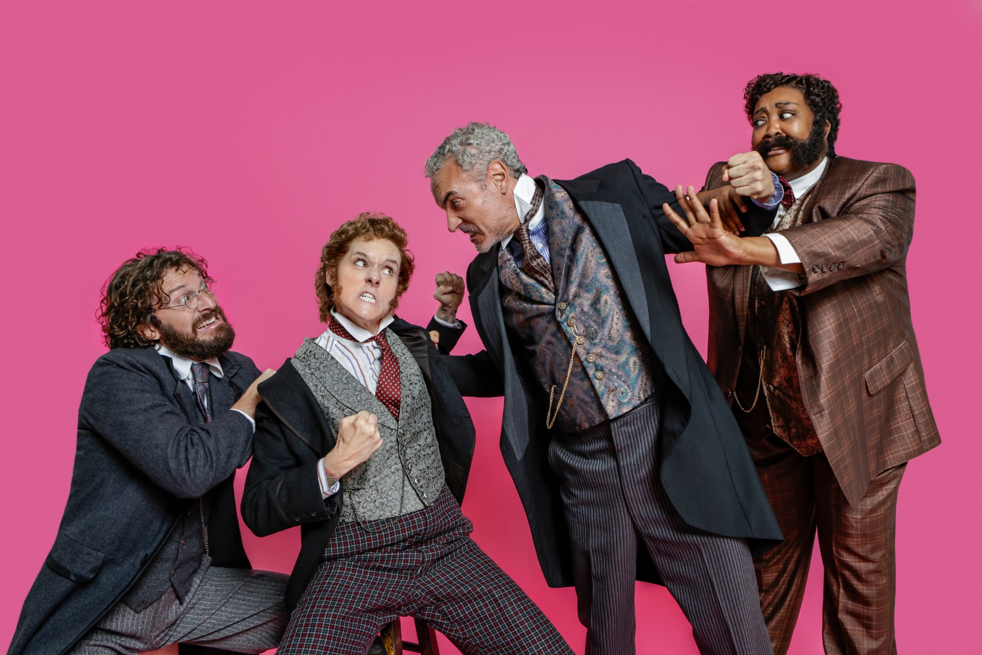 Four Ahoy-Hoy cast members pull one another into a comic tussle against a pink backdrop.